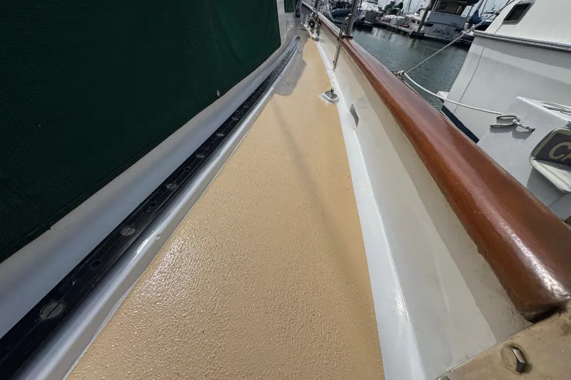 Slide: The Image of Deck view of 1988 Hans Christian Christina sailboat, featuring polished wood railing and textured surface. - 36