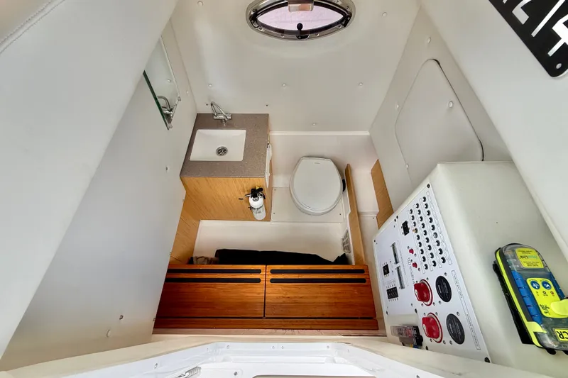 Slide: The Image of Interior of 2018 Wellcraft 302 Fisherman boat featuring a compact bathroom with sink and toilet. - 33