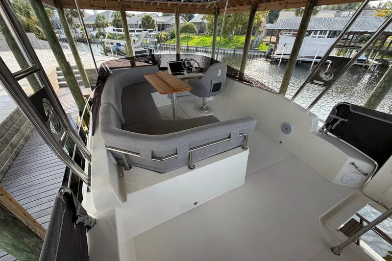 Slide: The Image of Flybridge of 2025 Beneteau Swift Trawler 35 with seating and table, docked by waterfront. - 15