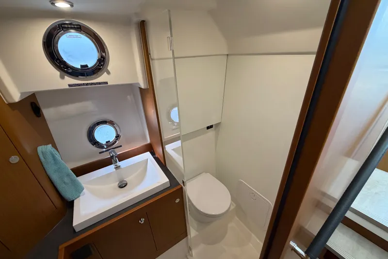 Slide: The Image of Bathroom interior of 2025 Beneteau Swift Trawler 35, featuring sink, toilet, and porthole windows. - 33