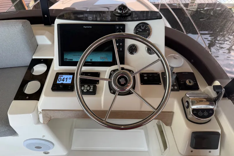 Slide: The Image of 2025 Beneteau Swift Trawler 35 helm with steering wheel and navigation controls. - 17