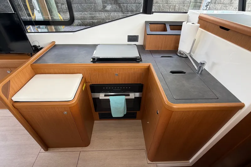 Slide: The Image of 2025 Beneteau Swift Trawler 35 kitchen with modern wood cabinetry and sleek countertops. - 24