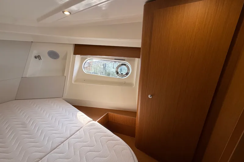 Slide: The Image of 2025 Beneteau Swift Trawler 35 cabin interior with wooden finishes and a porthole window. - 30
