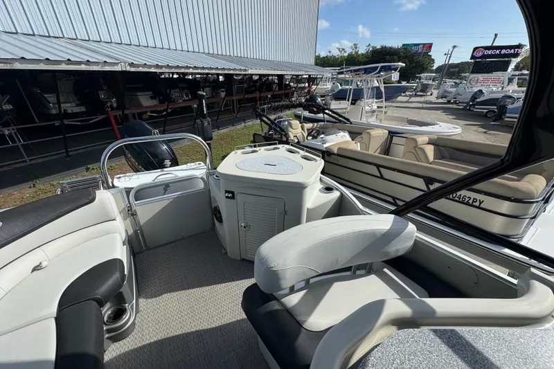 Slide: The Image of 2020 Avalon Catalina Platinum Entertainer boat interior with seating and helm, docked outdoors. - 7