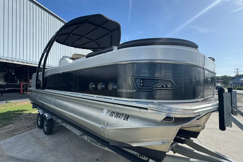 Slide: The Image of 2020 Avalon Catalina Platinum Entertainer 25' pontoon boat on trailer, parked outdoors. - 1