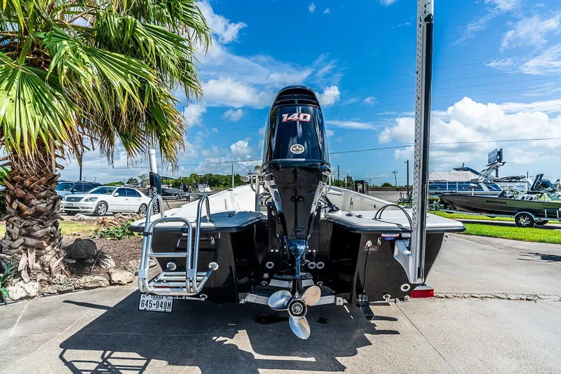 Slide: The Image of A 2018 Blue Wave 1900STL boat with an outboard motor, parked in a lot next to palm trees. - 4