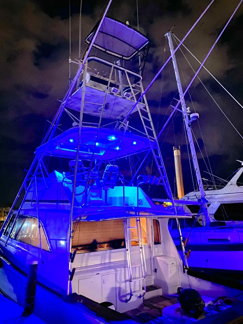 Slide: The Image of 1988 Ocean Yachts 48 Super Sport Convertible with blue night lighting at a marina. - 7