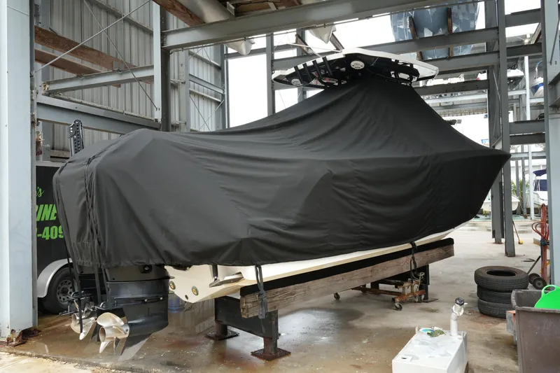 Slide: The Image of 2019 Blackfin 242 CC boat covered in black tarp, stored indoors on a wooden stand. - 56