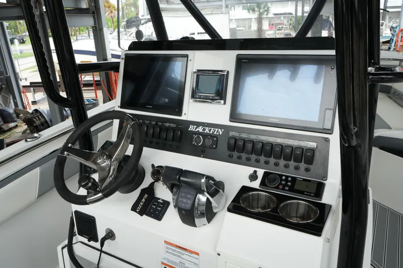 Slide: The Image of 2019 Blackfin 242 CC boat dashboard with steering wheel, dual screens, and control panel. - 39