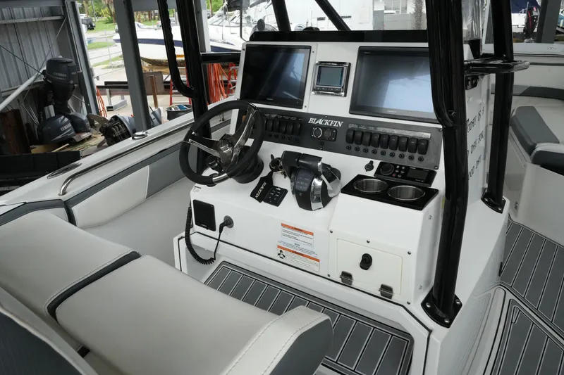 Slide: The Image of 2019 Blackfin 242 CC boat cockpit with steering wheel, dual screens, and control panel. - 17