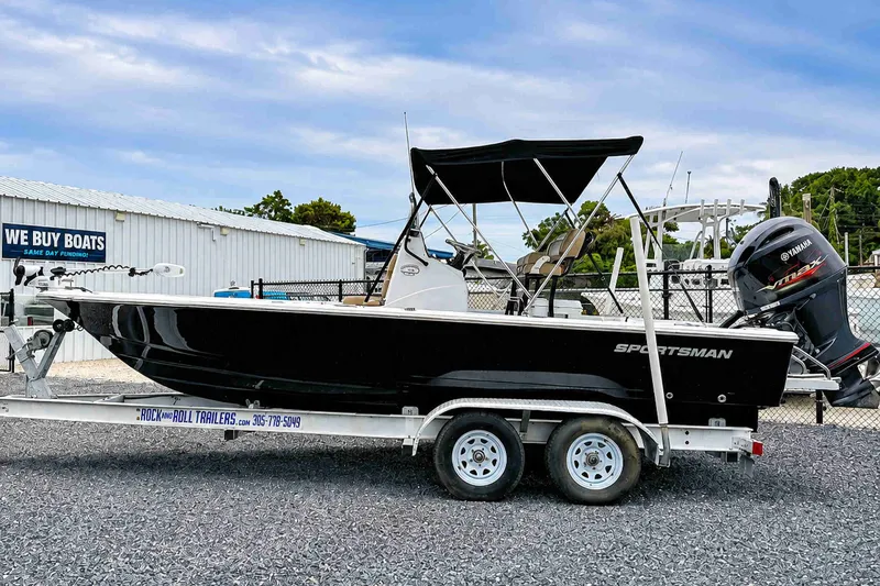The Image of 2019 Sportsman Tournament 214 SBX Bay Boat on trailer, parked near a boat dealership. - 0