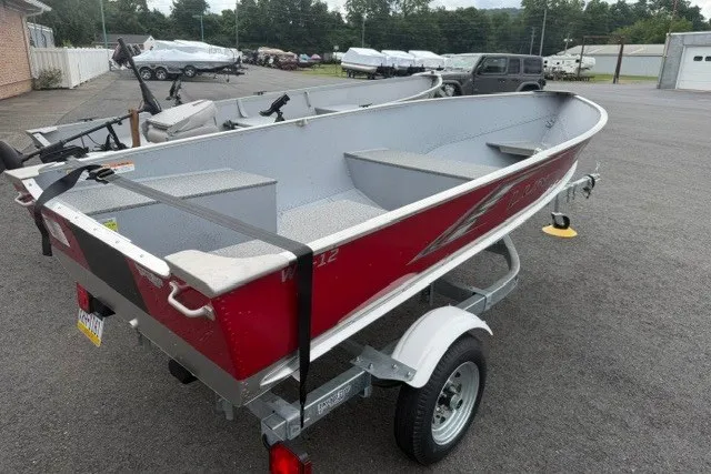 Slide: The Image of 2025 Lund WC-12 boat on trailer, red exterior, parked outdoors. - 7