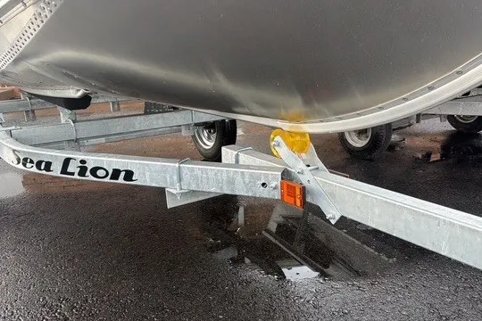 Slide: The Image of Trailer with Lund WC-12 boat, 2025 model, on wet pavement. - 8