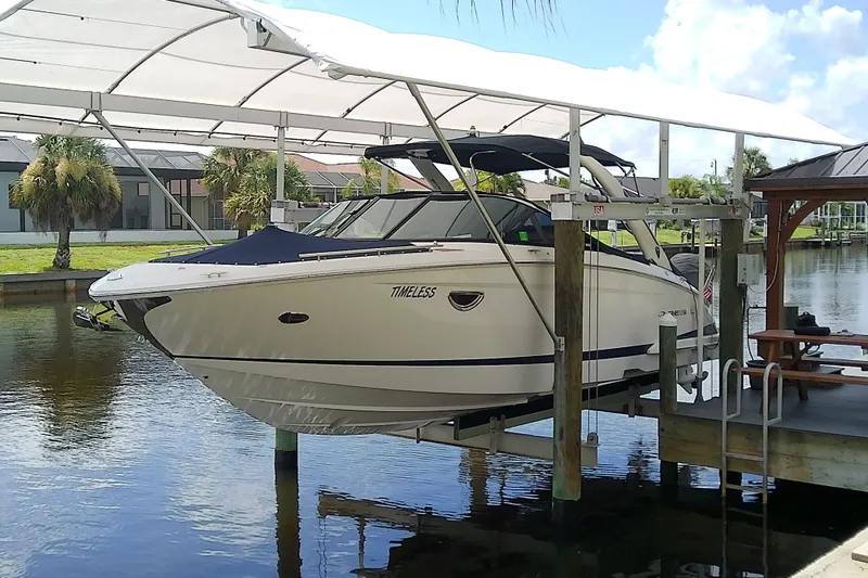 The Image of 2019 Regal 29 OBX boat docked under a canopy on a sunny day. - 0