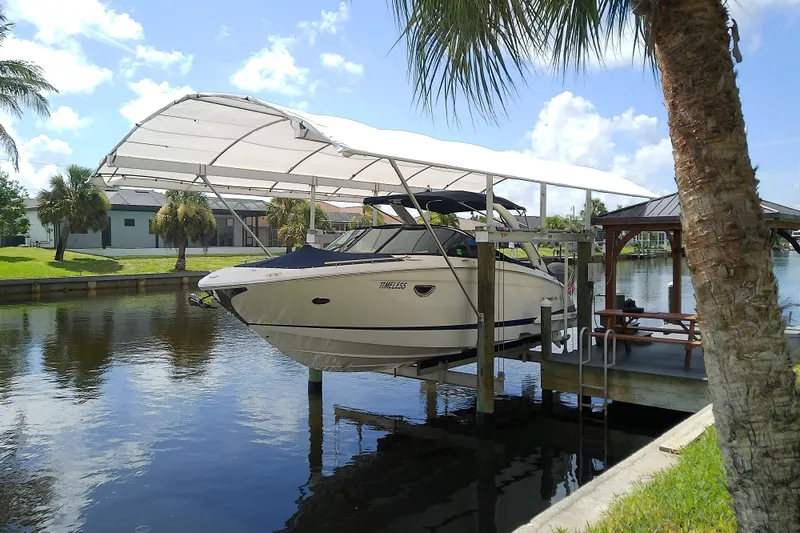 Slide: The Image of 2019 Regal 29 OBX boat docked under canopy by a canal with palm trees. - 5