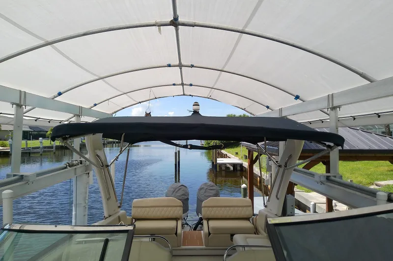 Slide: The Image of 2019 Regal 29 OBX boat under canopy, docked by a serene waterfront. - 42