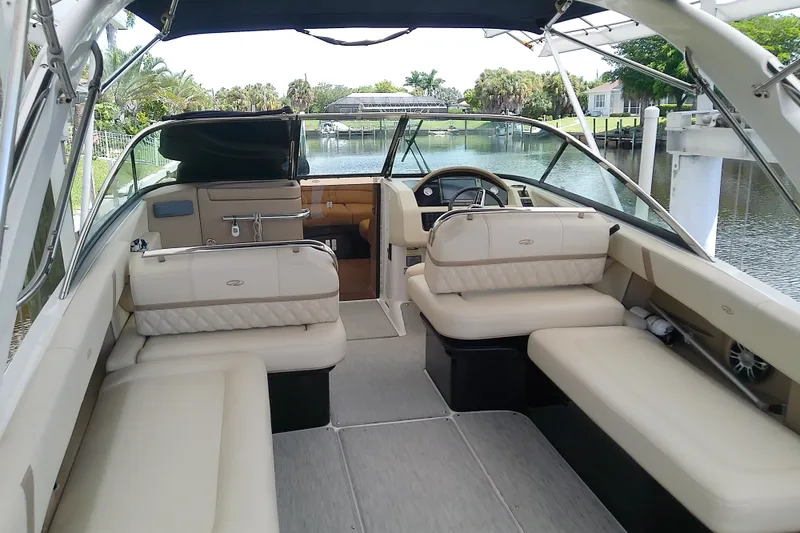 Slide: The Image of 2019 Regal 29 OBX boat interior with beige seating and steering wheel, docked by a canal. - 10