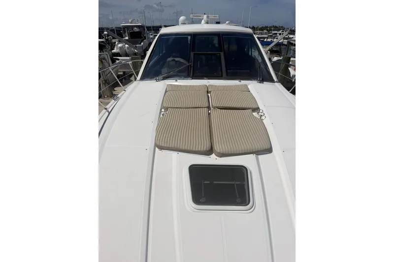Slide: The Image of 2013 Regal 52 Sport Coupe yacht with sun pads on deck, docked at marina. - 5