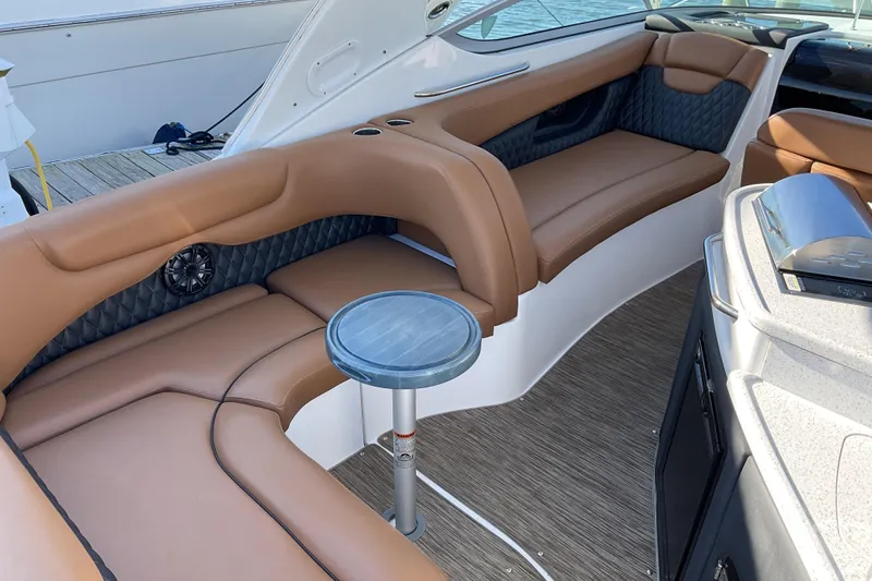 Slide: The Image of 2019 Rinker 290 Express Cruiser interior with brown seating and small table. - 3