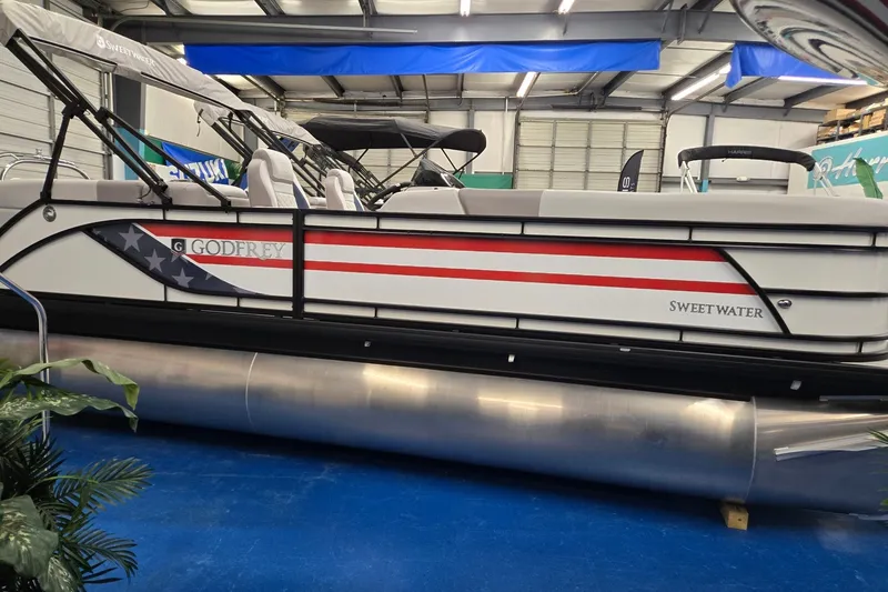 The Image of 2027 Godfrey Sweetwater 2286 SBC pontoon boat with American flag design in showroom. - 0