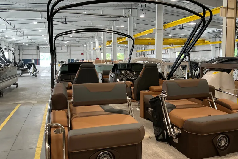 Slide: The Image of 2027 Avalon Catalina Platinum Quad Lounge boat interior in a spacious warehouse setting. - 4