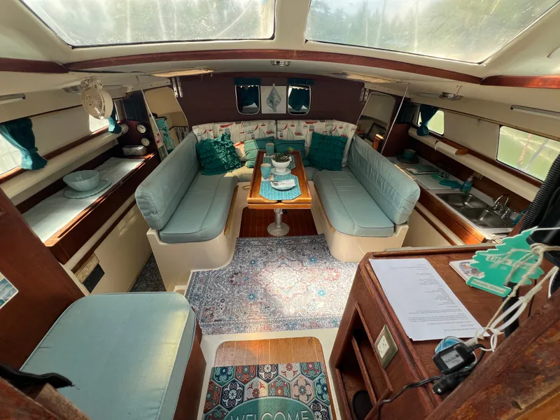 Slide: The Image of The interior of a 1993 Gemini Catamaran 3400 features a cozy seating area with a table and kitchenette. - 5