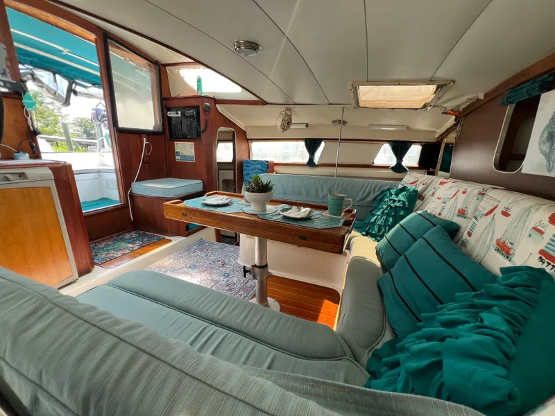 Slide: The Image of The interior of a 1993 Gemini Catamaran 3400 features a cozy seating area with cushions and a table. - 6