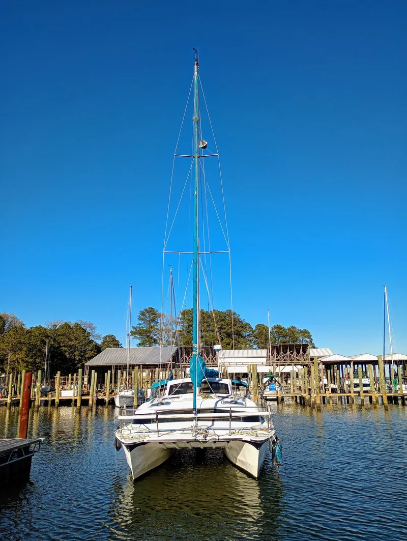Slide: The Image of A 1993 Gemini Catamaran 3400 is docked in the water, surrounded by piers and trees. - 1