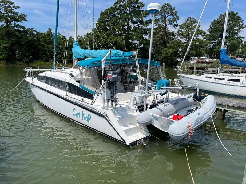 Slide: The Image of A 1993 Gemini Catamaran 3400 is docked in the water, featuring a dinghy and blue cover. - 2