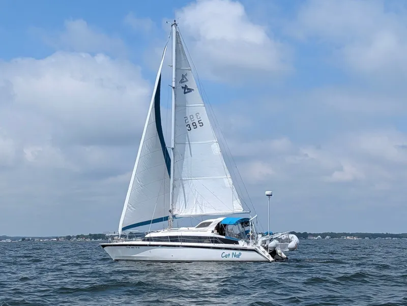 The Image of A 1993 Gemini Catamaran 3400 sails on calm waters under a blue sky. - 0