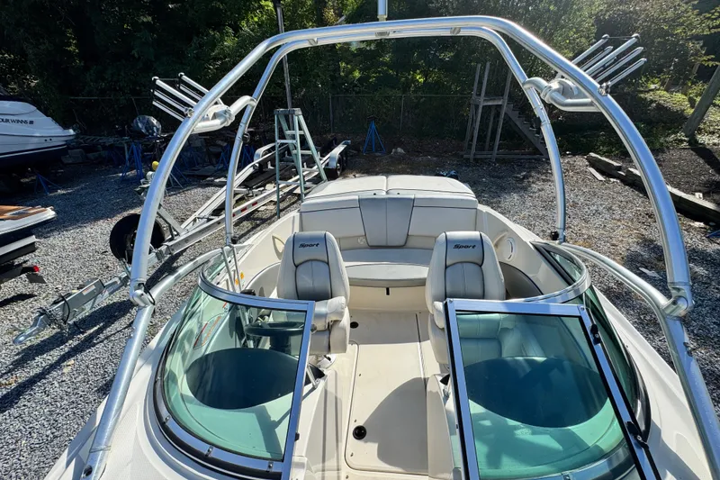 Slide: The Image of 2010 Sea Ray 185 Sport boat with open cockpit and seating, parked on gravel. - 6