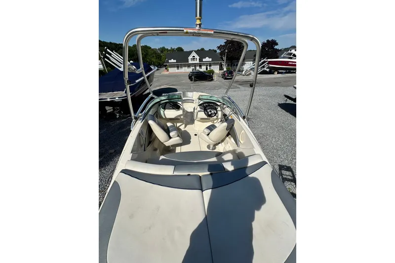 Slide: The Image of 2010 Sea Ray 185 Sport boat interior with steering wheel and seating, parked outdoors. - 3