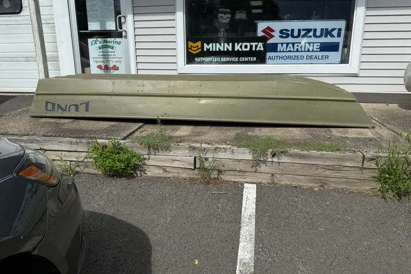 Slide: The Image of 2022 Lund 1240 boat displayed outside a marine service center. - 1