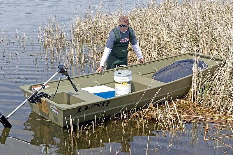 Slide: The Image of Manufacturer Provided Image: 2022 Lund 1240 boat in shallow water with a person and fishing gear. - 2