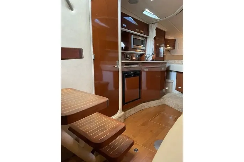 Slide: The Image of Interior of 2010 Sea Ray Sundancer 330 yacht, featuring a compact kitchen and wooden stairs. - 16