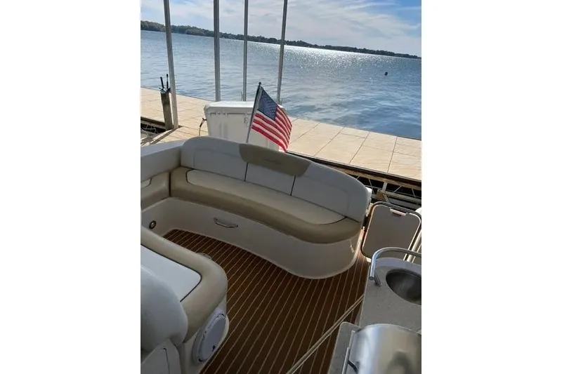 Slide: The Image of 2010 Sea Ray Sundancer 330 boat interior with seating, docked by a serene lake. - 8
