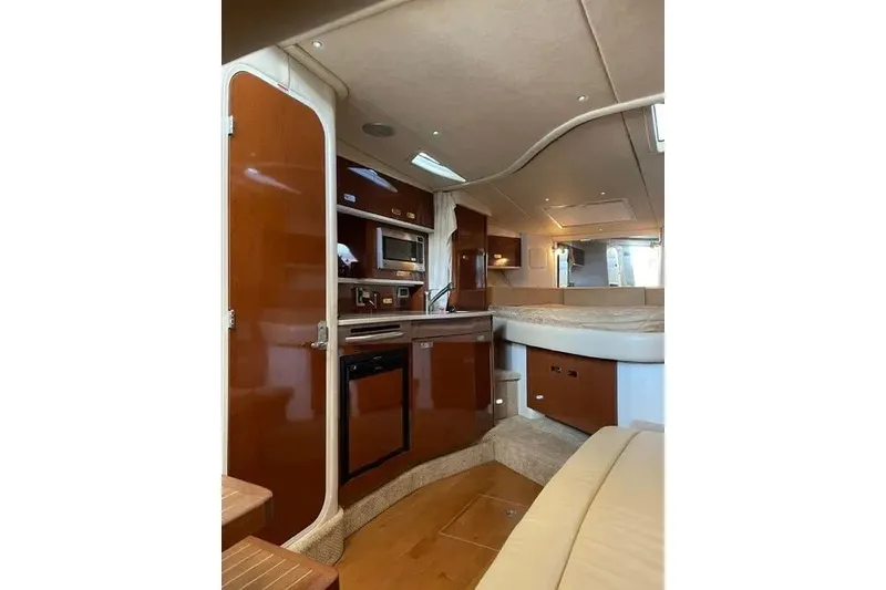 Slide: The Image of Interior of 2010 Sea Ray Sundancer 330 yacht, featuring a compact kitchen and cozy seating area. - 17