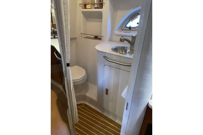 Slide: The Image of 2010 Sea Ray Sundancer 330 bathroom with sink, toilet, and porthole window. - 13