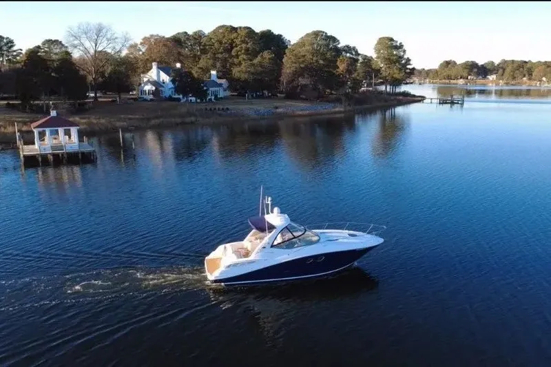 Slide: The Image of 2010 Sea Ray Sundancer 330 cruising on a serene lake near a wooded shoreline. - 2