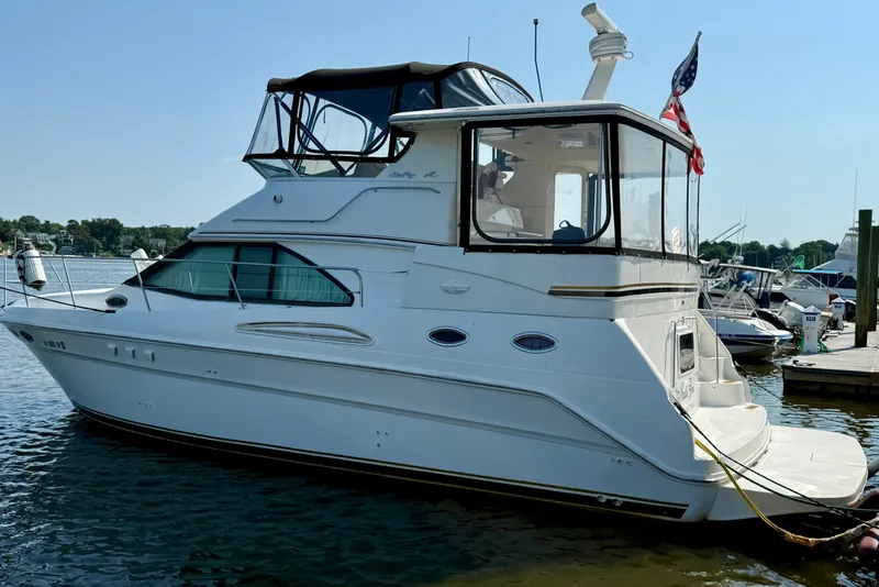 The Image of Sea Ray 380 Aft Cabin 2000 yacht docked at marina, featuring sleek design and American flag. - 0