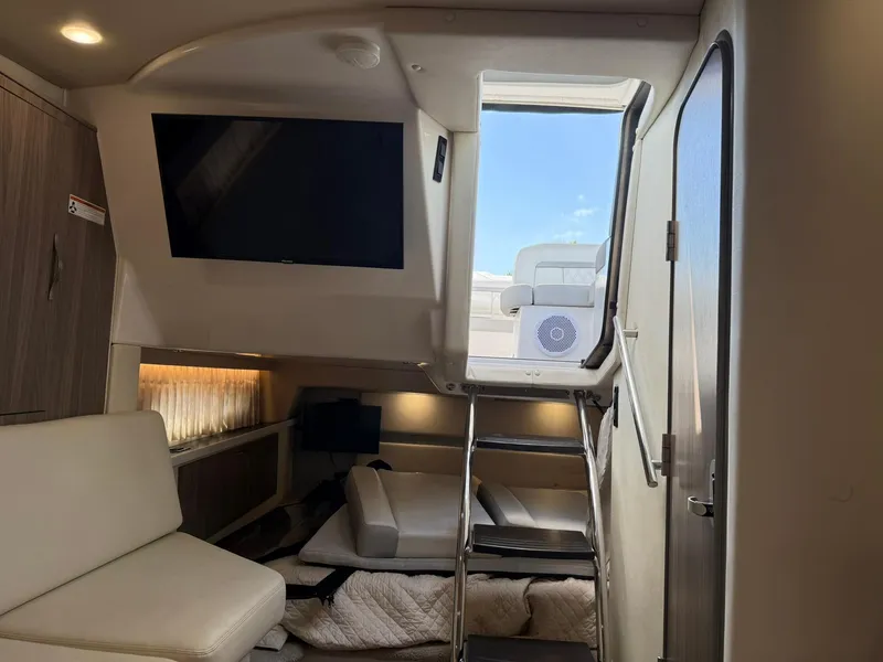 Slide: The Image of 2021 Regal 33 XO cabin interior with TV, seating, and ladder to deck. - 15