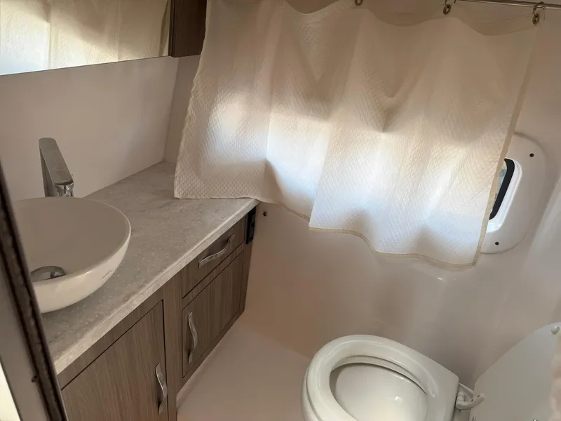 Slide: The Image of 2021 Regal 33 XO boat bathroom with sink, toilet, and curtain. - 20