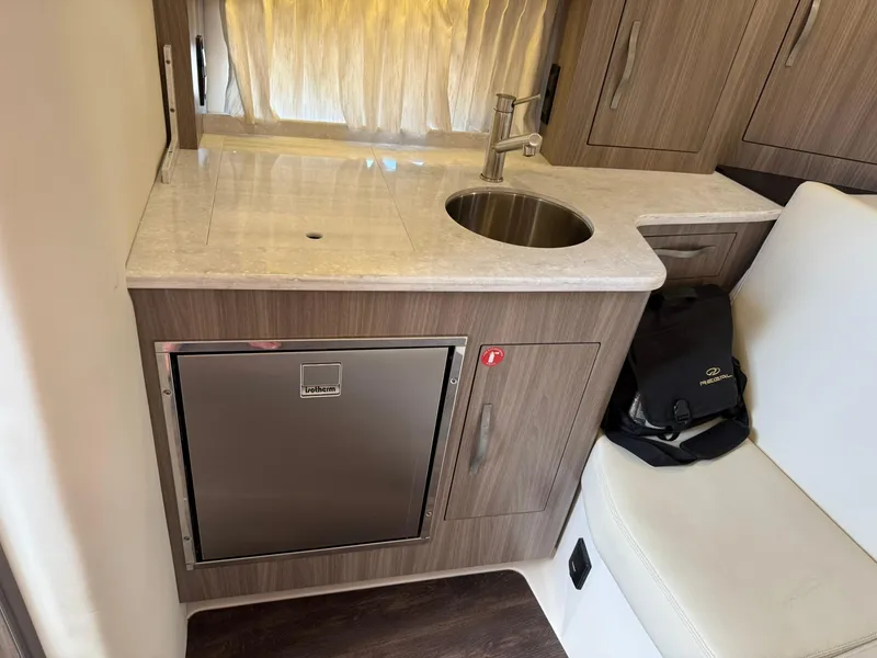 Slide: The Image of 2021 Regal 33 XO boat interior with kitchenette, sink, and compact fridge. - 18