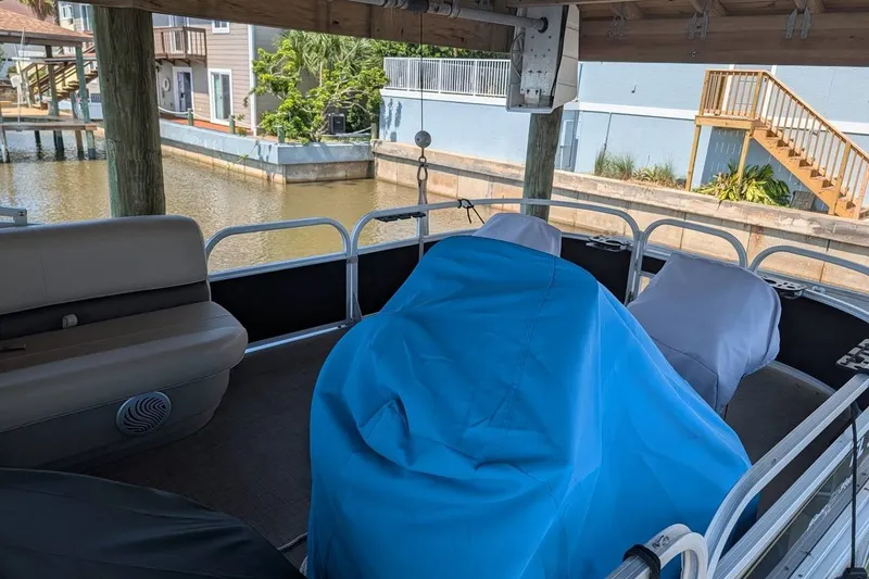 Slide: The Image of 2021 Sun Tracker Bass Buggy 16 XL pontoon boat with covered seats, docked by a canal. - 15
