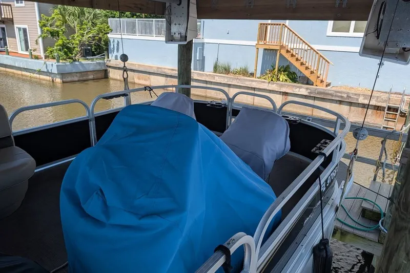 Slide: The Image of 2021 Sun Tracker Bass Buggy 16 XL pontoon boat covered and docked by a canal. - 14