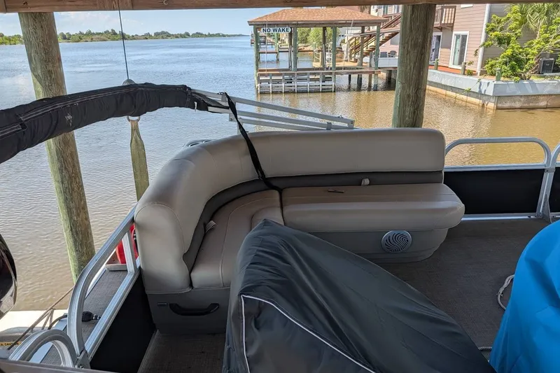 Slide: The Image of 2021 Sun Tracker Bass Buggy 16 XL pontoon boat interior by a serene waterfront. - 16