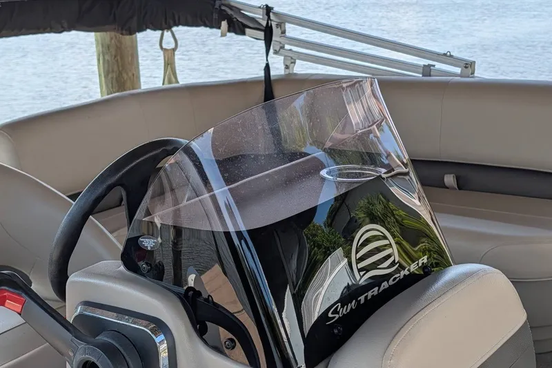 Slide: The Image of 2021 Sun Tracker Bass Buggy 16 XL steering console with windshield, docked by water. - 21