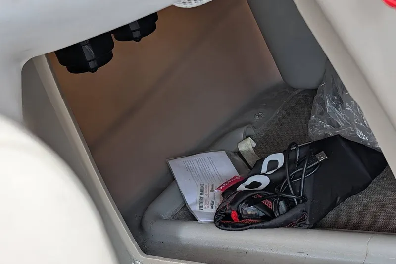 Slide: The Image of Storage compartment in a 2021 Sun Tracker Bass Buggy 16 XL with cables and documents. - 24