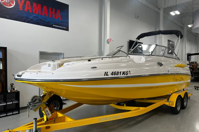 The Image of 2008 Starcraft 2410 IO Limited boat in showroom, yellow and white, on trailer. - 2