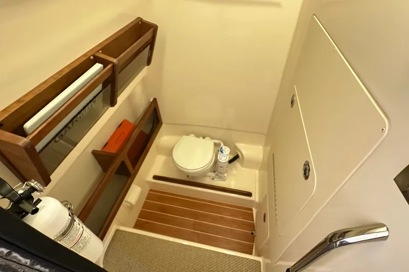 Slide: The Image of 2023 Grady-White 281 Coastal Explorer boat bathroom with wooden accents and storage shelves. - 52